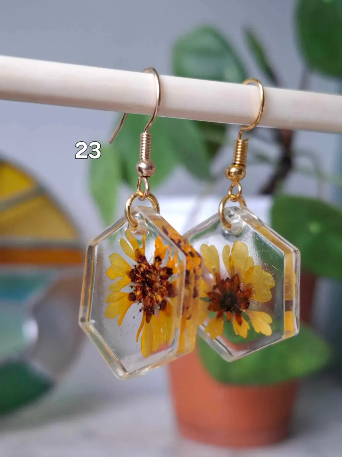 Boucles d'oreilles hexagonales en résine transparente avec de véritables fleurs jaunes séchées.