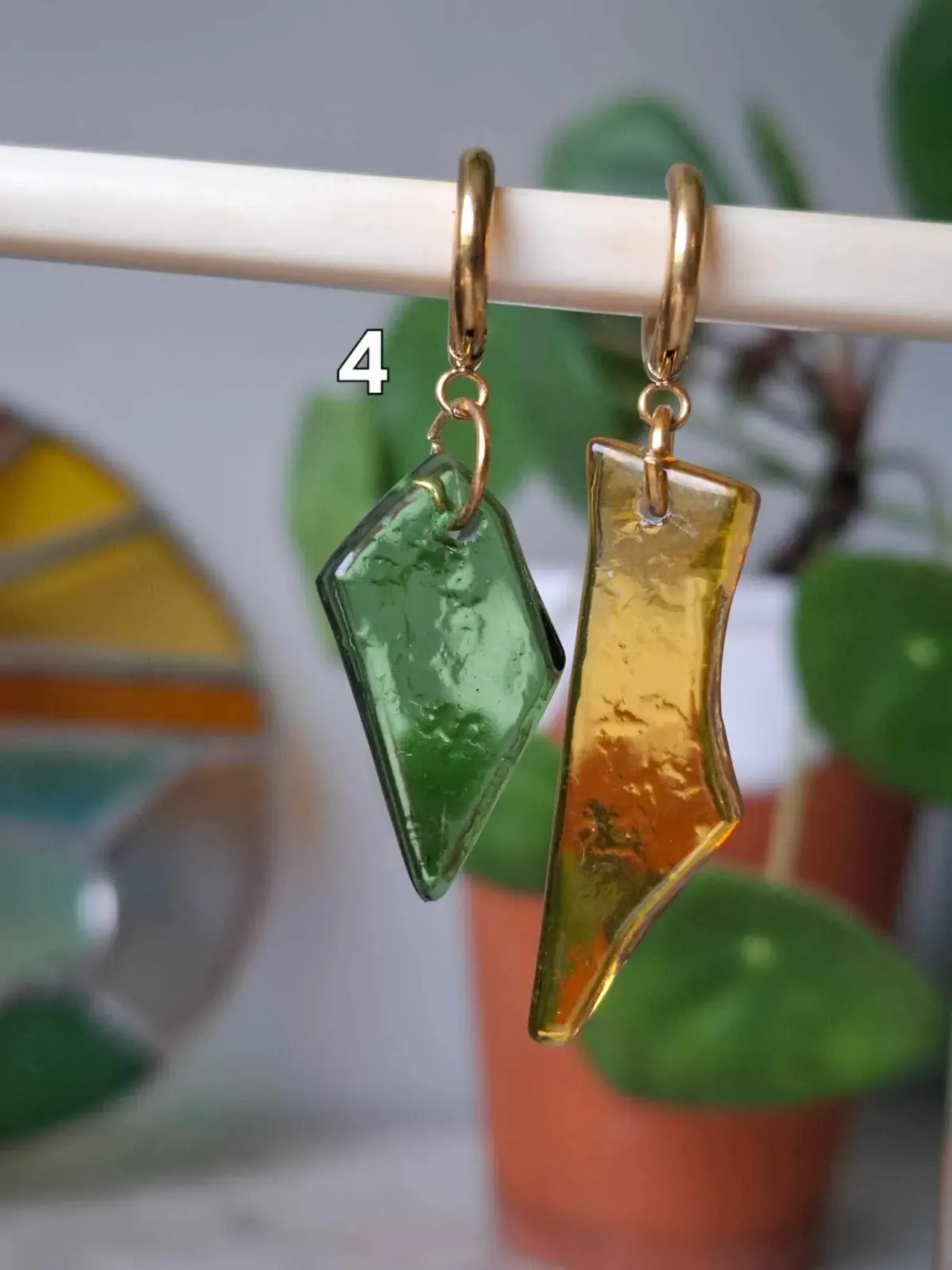 Boucles d'oreilles asymétriques suspendues, l'une en verre vert et l'autre en verre jaune ambré.