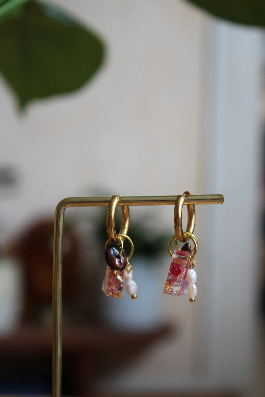 Boucles d'oreilles créoles dorées suspendues, avec pendentifs triangulaires roses, perles blanches et pierres.