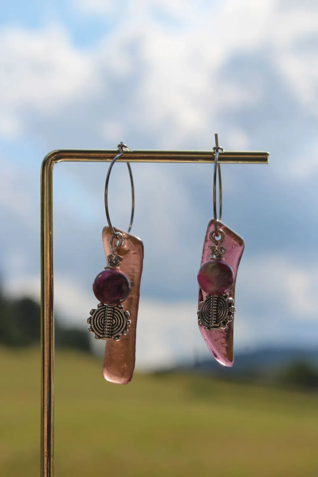Boucles d'oreilles pendantes en verre rose et perles violettes suspendues sur un support doré.