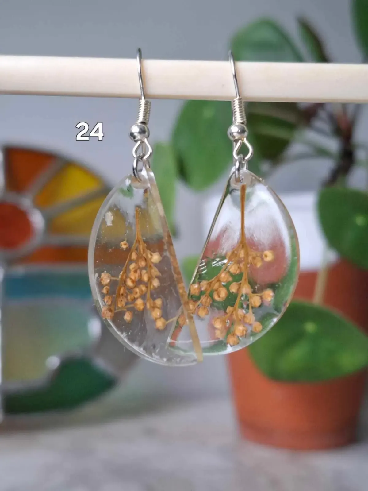 Boucles d'oreilles demi-lune transparentes en résine avec de petites fleurs séchées jaunes suspendues.