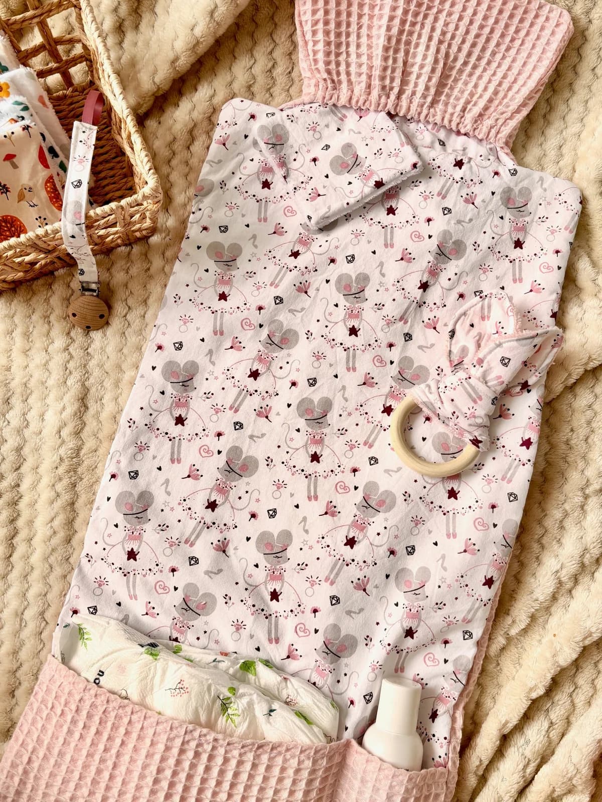 Tapis à langer ouvert à motif souris ballerines et tissu nid d'abeille rose avec hochet en bois.