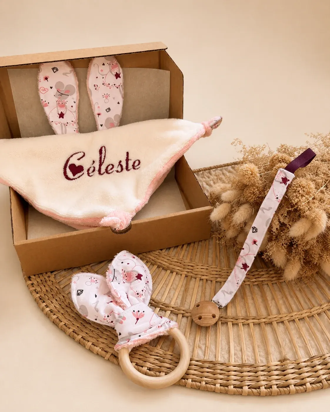 Coffret cadeau ouvert contenant le doudou brodé Céleste, le hochet et l'attache-tétine.