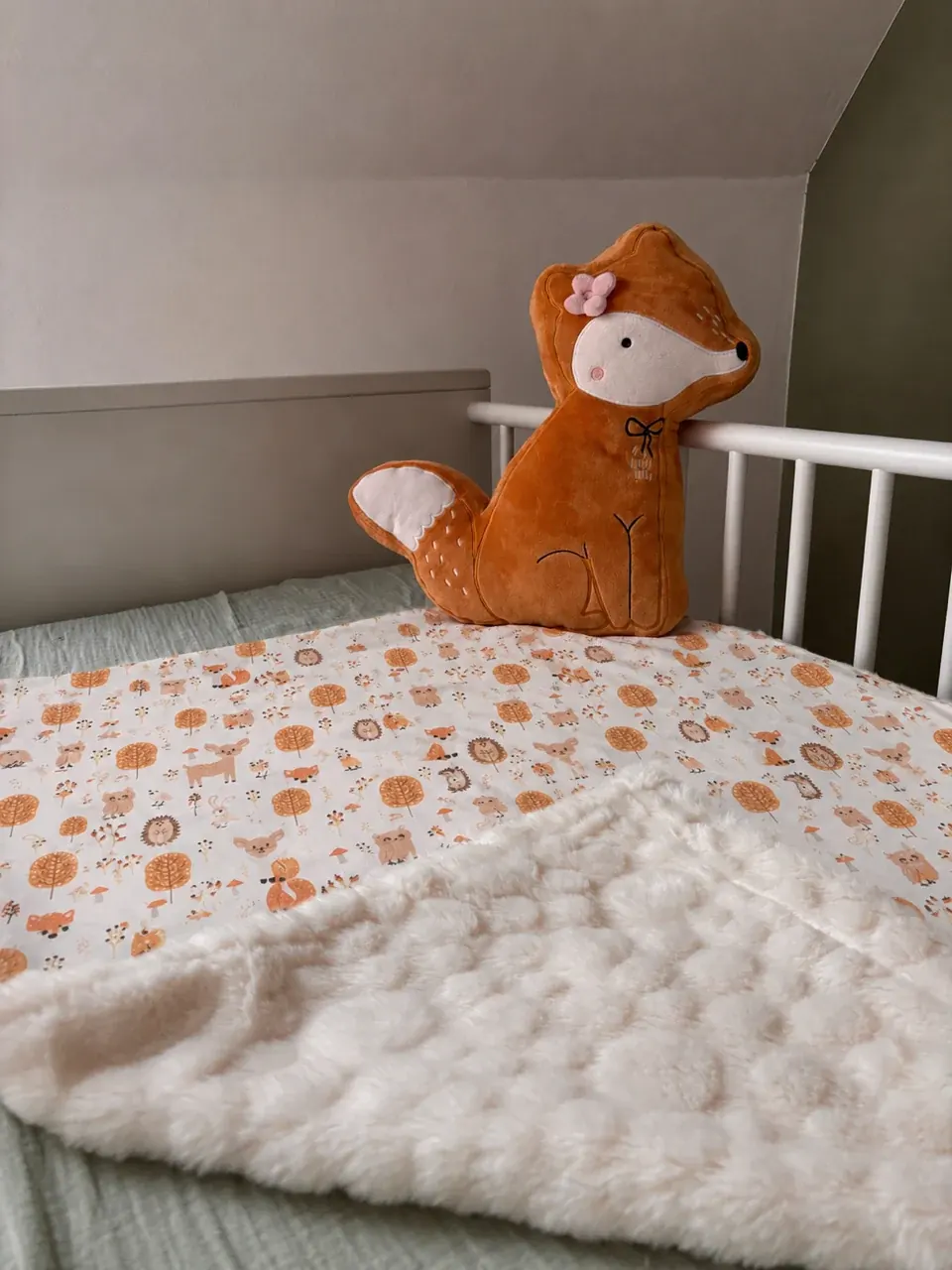 Couverture bébé sur un panier en osier, révélant sa doublure blanche texturée et ses motifs d'animaux.