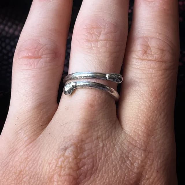 Bague réglable en argent en forme d'allumette qui s'enroule autour du doigt, vue de face.