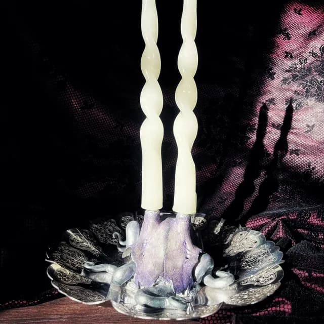 Bougeoir avec deux bougies torsadées blanches sur un socle en os violet et une coupelle argentée ciselée.