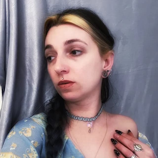 Femme portant le ras de cou tissé bleu et doré orné d'un pendentif en cristal irisé.