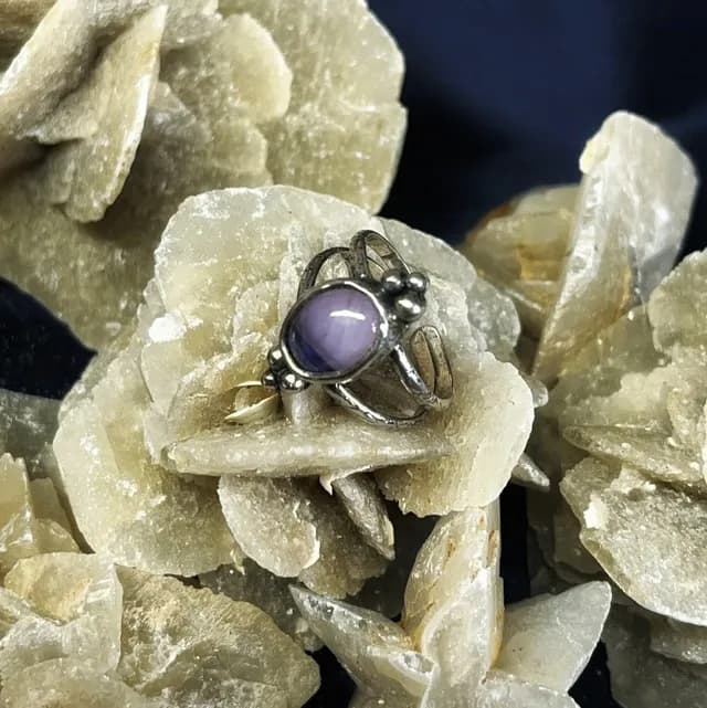 Bague en argent avec pierre violette ovale posée sur une rose des sables.