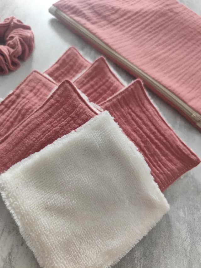 Gros plan sur l'empilement de lingettes lavables roses avec face douce blanche, pochette rose en fond.