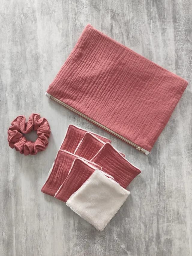 Pochette zippée rose, chouchou assorti et lingettes réutilisables roses et blanches à plat.